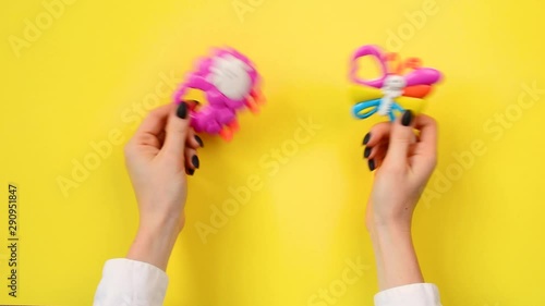 Mother shakes baby rattle on a yellow background 