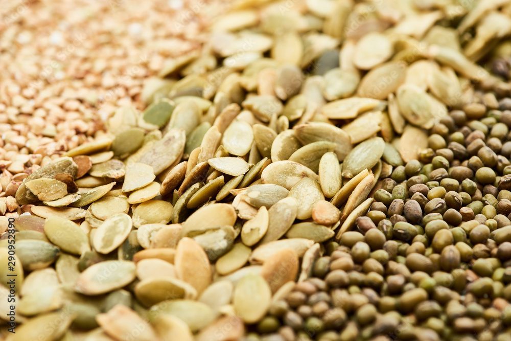 close up view of raw pumpkin seeds near maash and green buckwheat close up view of raw pumpkin seeds near maash and green buckwheat