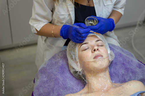 Beauty Clinic.woman gets a professional facial procedure. Beautician makes massage on a woman's face. face renewal