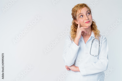 Portrait of beautiful blonde woman doctor thinking and looking up