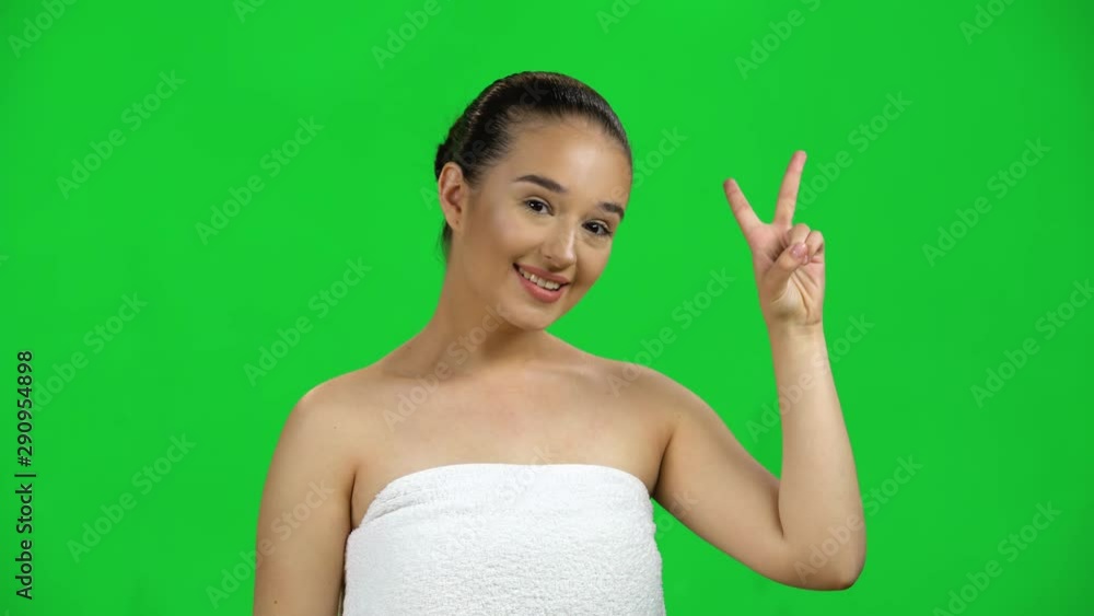 Cheerful girl shows two fingers victory gesture, isolated on green screen at studio Cheerful girl shows two fingers victory gesture, isolated on green screen at studio