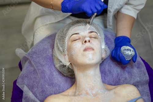 Beautician makes facial massage to a woman.