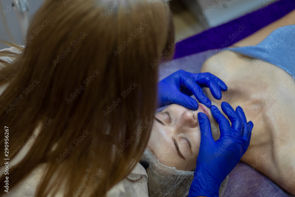 Fototapeta premium Beauty Clinic.woman gets a professional facial procedure. Beautician makes massage on a woman's face. face renewal