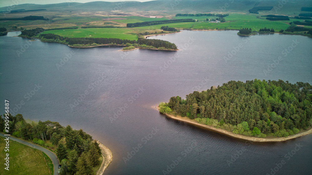 A blue loch with islands on green Scotish landscape