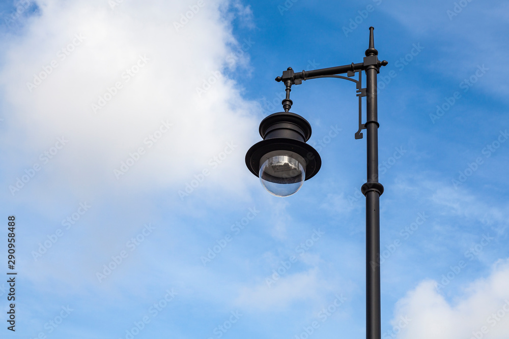 Old-fashioned street lamp against the blue sky with white clouds