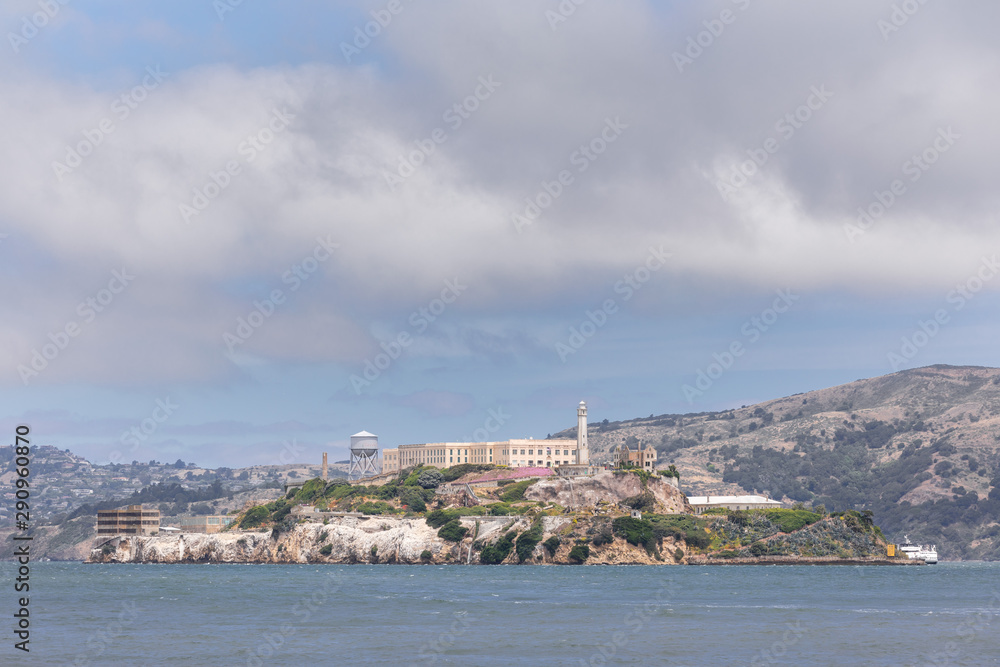 Close up of the Alcatraz island in San Francisco bay, under a blue sky with thick puffy clouds