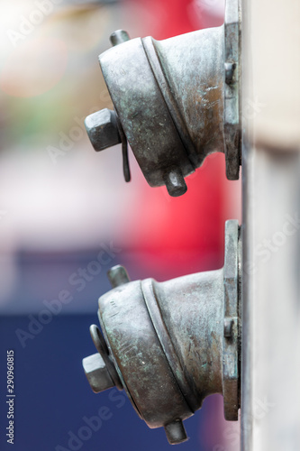 Close up of two wall-mounted brass fire hydrants, against a bokeh background