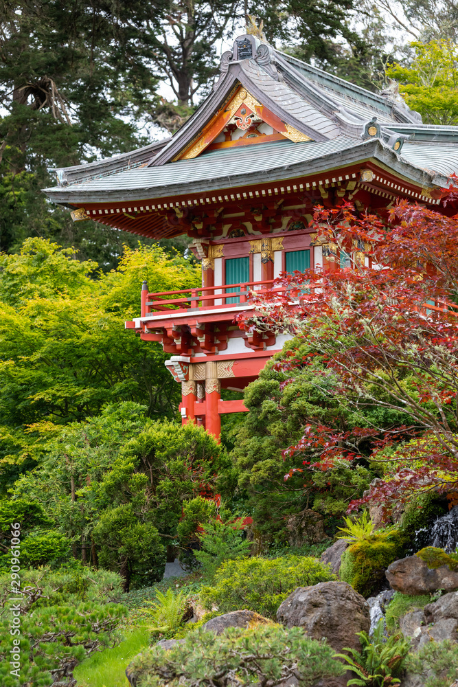 A red japanese pagoda temple surrounded by green vegetation and moss-covered rocks A red japanese pagoda temple surrounded by green vegetation and moss-covered rocks
