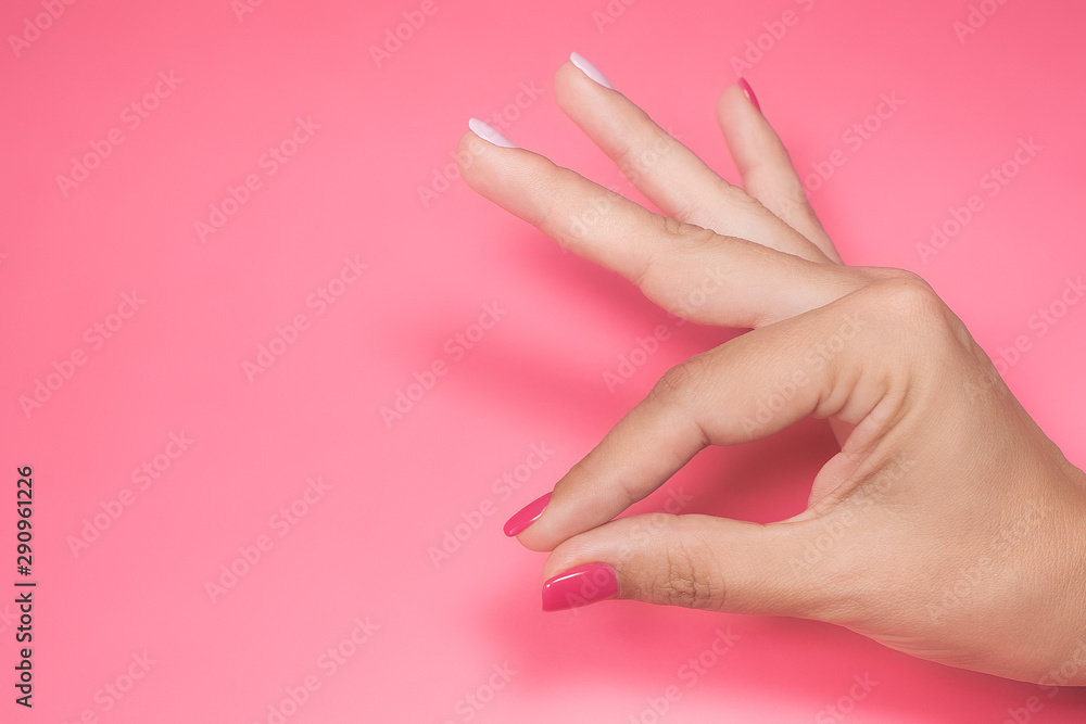 Closeup view of beautiful manicured female hand isolated on bright pink background. Horizontal color photography.