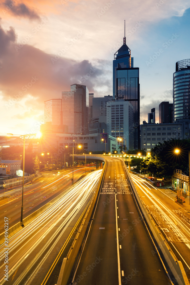 Fototapeta premium Light trails of traffic in Hong Kong at sunset time with Hong Kong bussines center in background. Asia. Asian tourism, modern city life, or business finance and economy concept