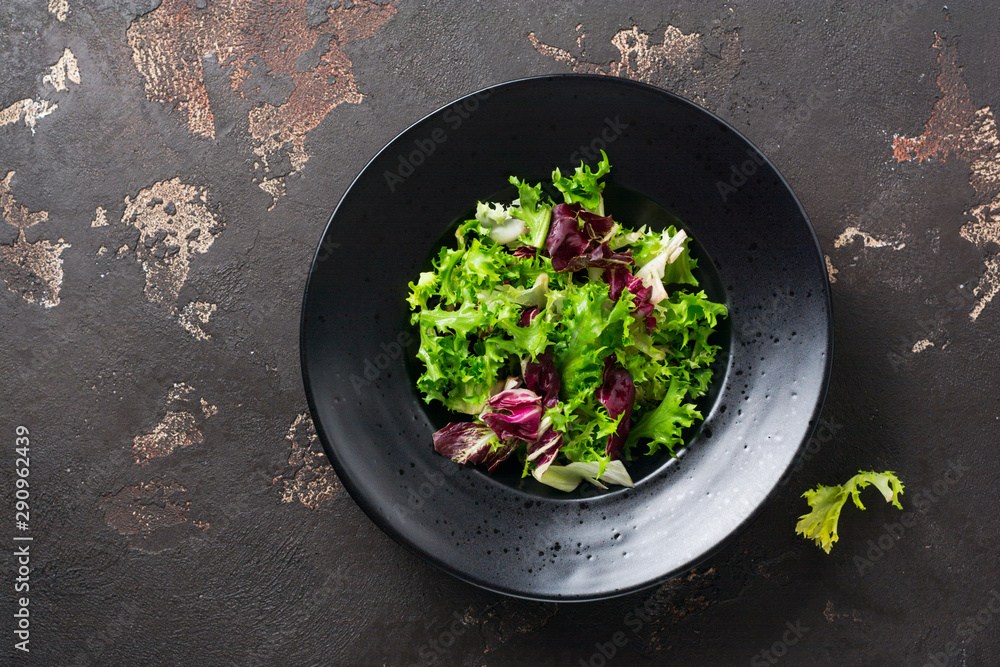 Mix fresh leaves of arugula, lettuce, spinach, beets for salad on a dark stone background. Selective focus. Mix fresh leaves of arugula, lettuce, spinach, beets for salad on a dark stone background. Selective focus.