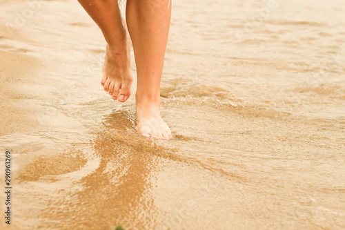 Female legs in the sand. Human foot. Sea. Advertising