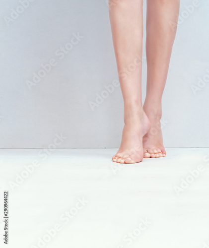 Female slender legs  feet are on the light gray background floor. Fitness  health  sexuality  medicine  fungal diseases