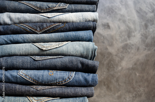A stack of neatly folded jeans on gray background. Close-up of jeans in different colors. Jeans texture or denim background. Copy space