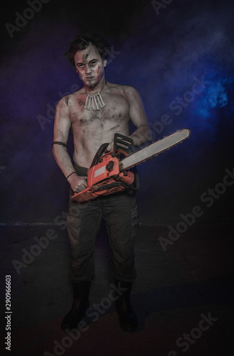 Картината върху платно Terrible man with chainsaw standing in blue fog