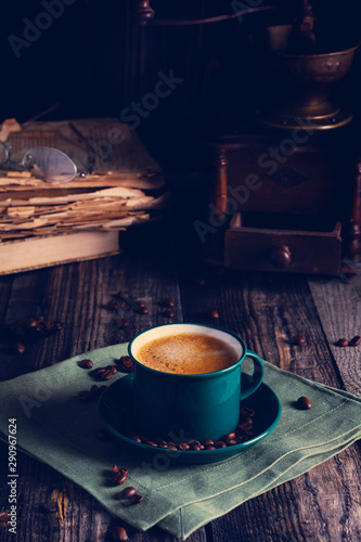 Cafe background with a green cup of espresso coffee standing on a linen napkin with a retro coffee grinder old book. Retro style Nashville. Tonted image. photo