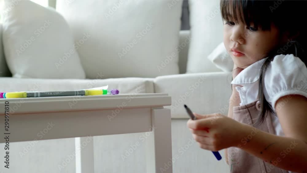 A single mother of Asian ethnic teaching her daughter to draw at home on a beautiful morning sunshine through the large living room window A single mother of Asian ethnic teaching her daughter to draw at home on a beautiful morning sunshine through the large living room window