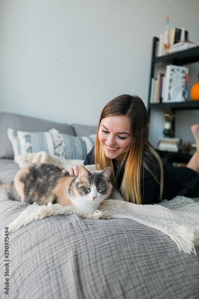 Cute girl cuddling with calico cat on bed in apartment, copy space, sweet Cute girl cuddling with calico cat on bed in apartment, copy space, sweet