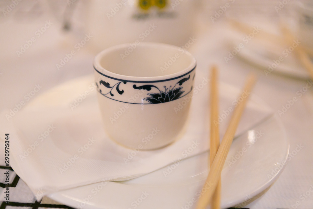 Mug sitting on a white plate next to chopsticks Mug sitting on a white plate next to chopsticks