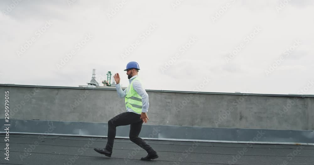 Dancing at construction site a charismatic construction worker or engineer in a safety helmet he moving funny on the rooftop of construction site Dancing at construction site a charismatic construction worker or engineer in a safety helmet he moving funny on the rooftop of construction site