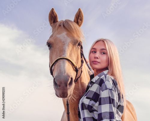 portrait of a young blonde girl with a beige horse on the ranch close up