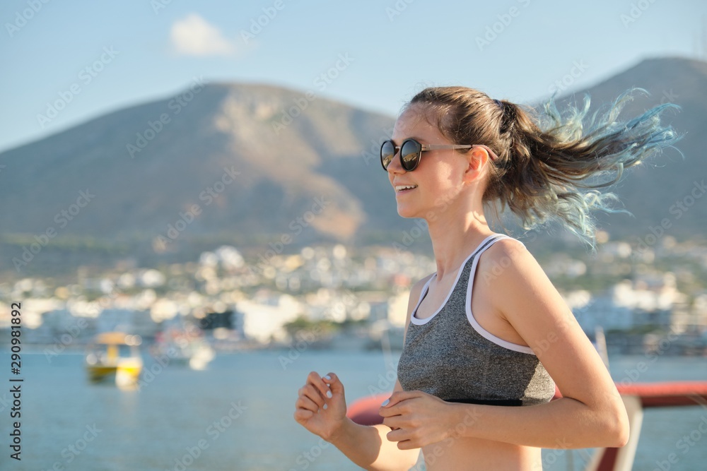 Teenager girl running jogging in seaside promenade