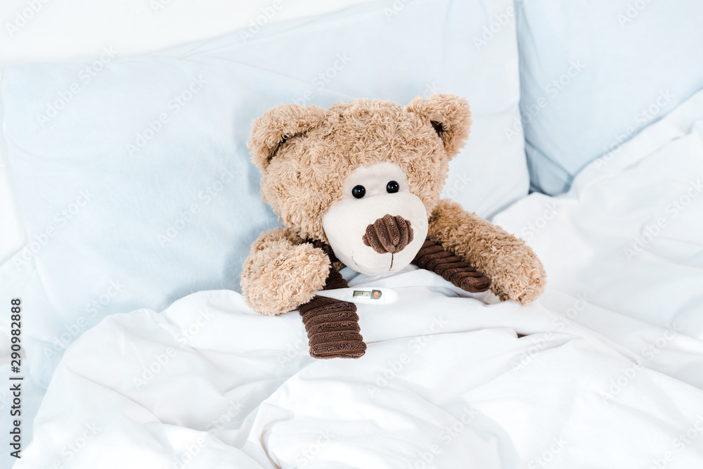 teddy bear on bed with white bedding and pillows