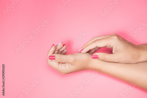 Woman demonstrating two beautiful hands with trendy colorful pink and purple manicure isolated on pink background. Top view flat lay horizontal color photography.
