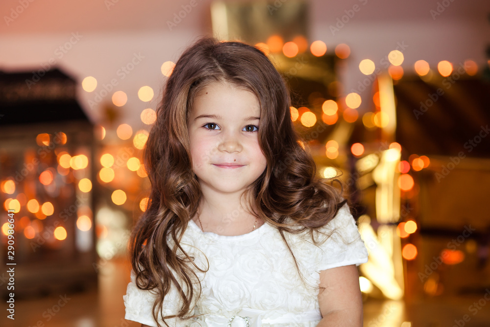 portrait of a happy cute girl of 6-7 years old in a white elegant dress in the New Year’s party waiting for a merry Christmas portrait of a happy cute girl of 6-7 years old in a white elegant dress in the New Year’s party waiting for a merry Christmas