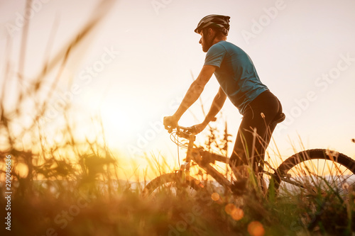 Foto Man biker man meets a sunset in top of hill over the city