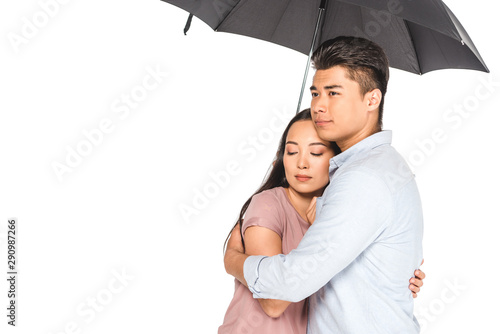 handsome asian man hugging pretty girlfriend while standing under umbrella isolated on white