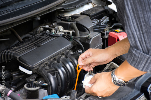 Man or auto mechanic worker hands checking the car engine oil and maintenance before traveling for safety.