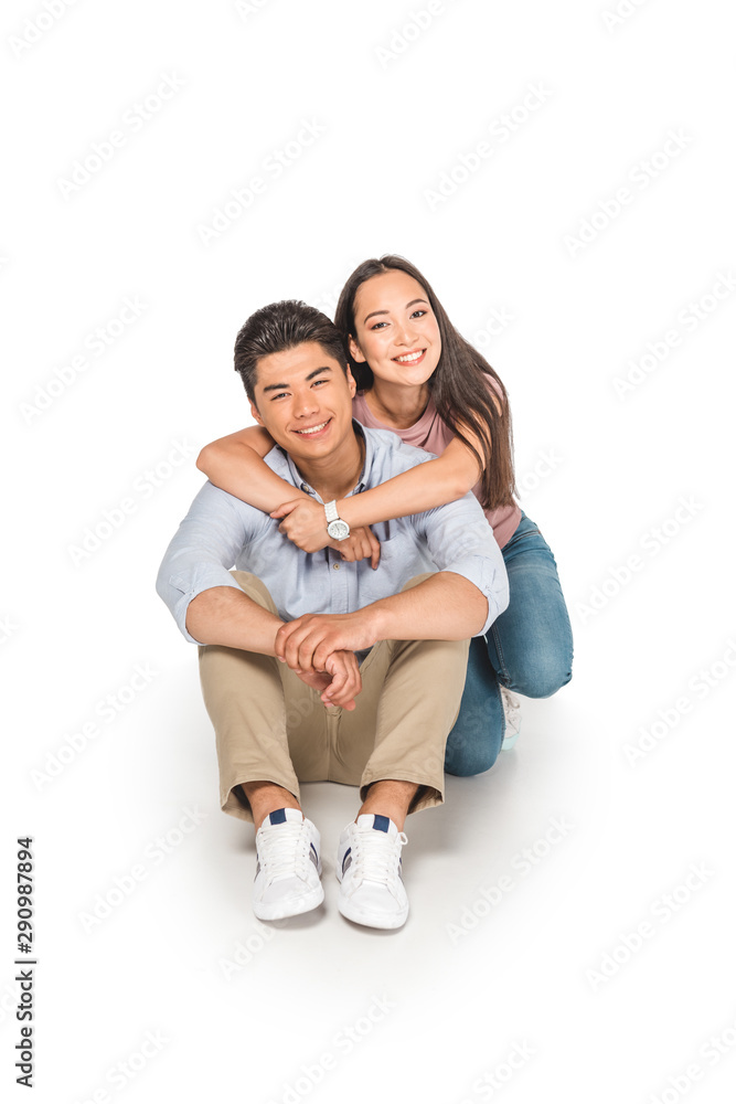 happy asian girl hugging boyfriend while sitting on white background happy asian girl hugging boyfriend while sitting on white background