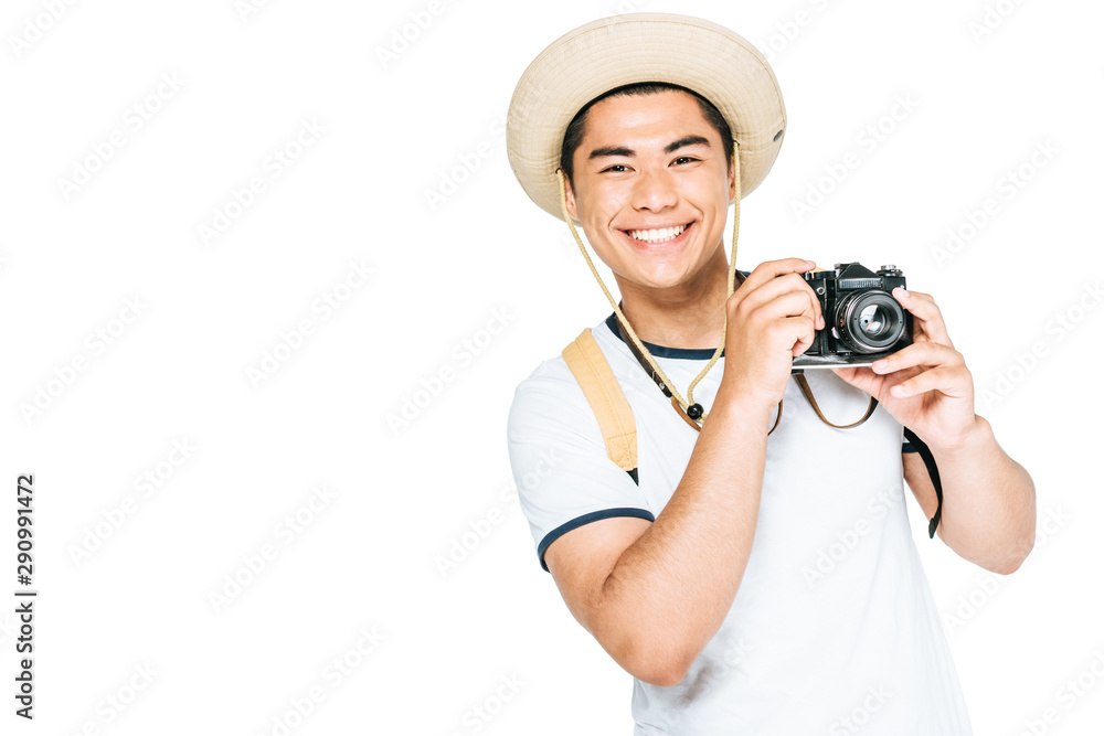 happy asian tourist in hat holding digital camera and smiling at camera isolated on white happy asian tourist in hat holding digital camera and smiling at camera isolated on white