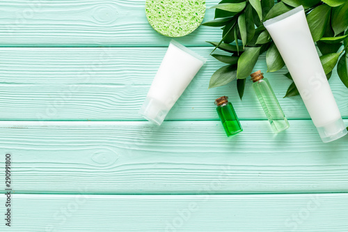 Cosmetics for face with cream, lotion from herbs, sponge on mint green wooden background top view copyspace photo