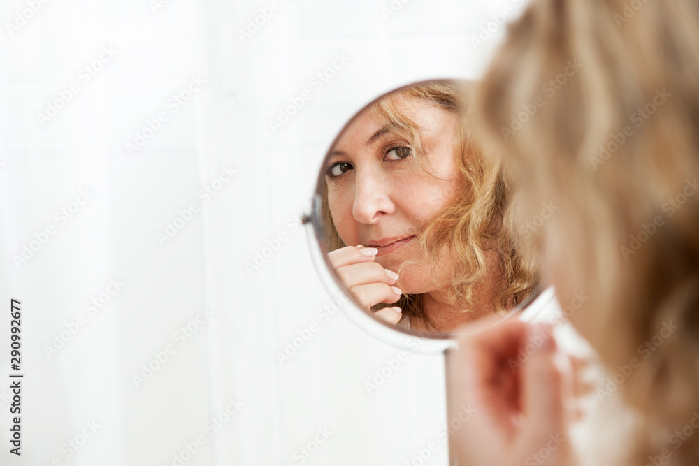 Beautiful mature Caucasian woman looking in the mirror Beautiful mature Caucasian woman looking in the mirror