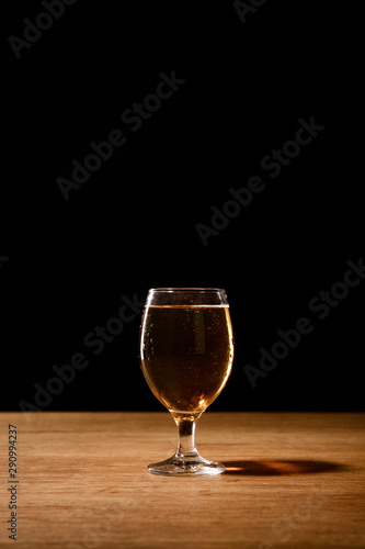 glass of fresh beer on wooden table isolated on black