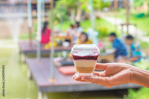 Hand holding cake Background blur people and tree in garden on pond.