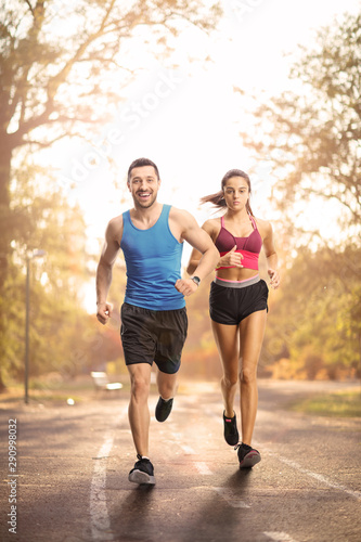 Young man and woman in sportswear running outdoors on a sunset