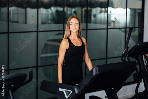 blonde woman training on a treadmill inside a gym © dark_saiyaman