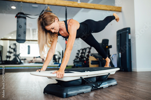 Photography woman training doing plank exercises on a surfboard in the gym