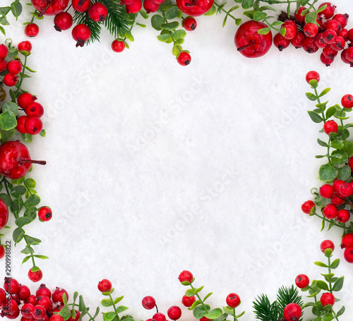 Christmas decoration. Frame of red berries, small red apples and twigs christmas tree on snow with space for text. Top view, flat lay