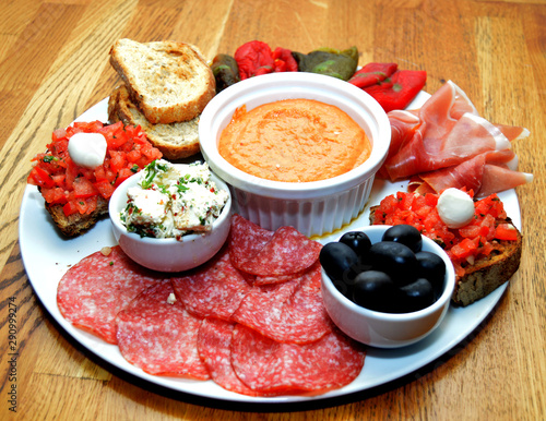 Close up of mixed platter with various cheeses, olives, peppers, toast and cured meats 