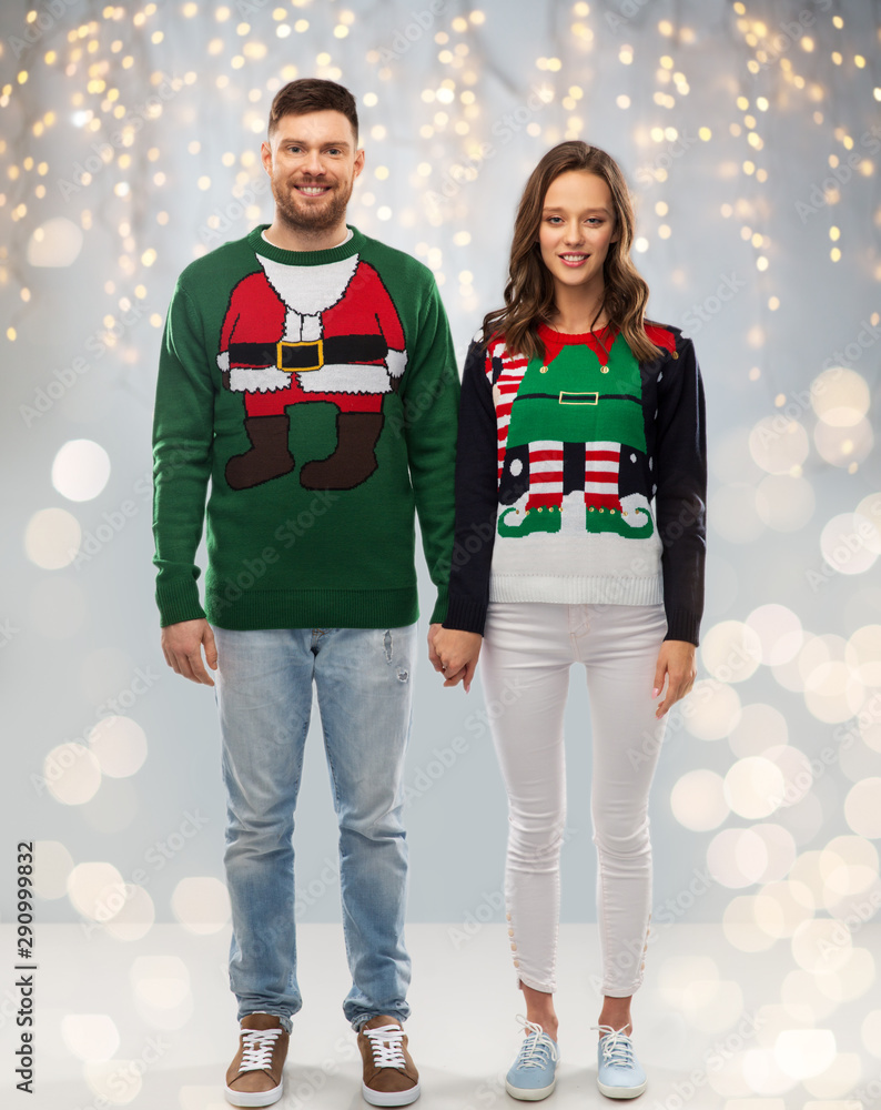 christmas, people and holidays concept - happy couple at ugly sweater party over festive lights background christmas, people and holidays concept - happy couple at ugly sweater party over festive lights background