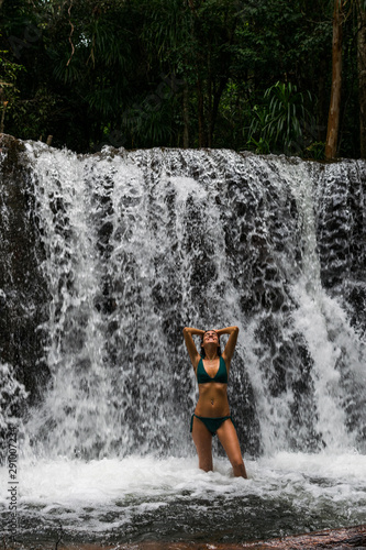 Fototapeta Naklejka Na Ścianę i Meble -  Imagen de una joven mujer en bikini en una cascada en una reserva natural de la isla de Phu Quoc en Vietnam durante el verano