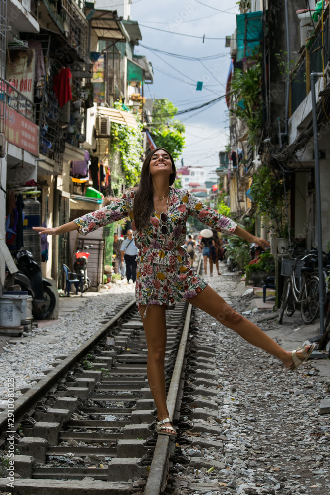 Imagen de una joven mujer sonriendo y paseando por las vías del tren del centro de la ciudad de Hanoi