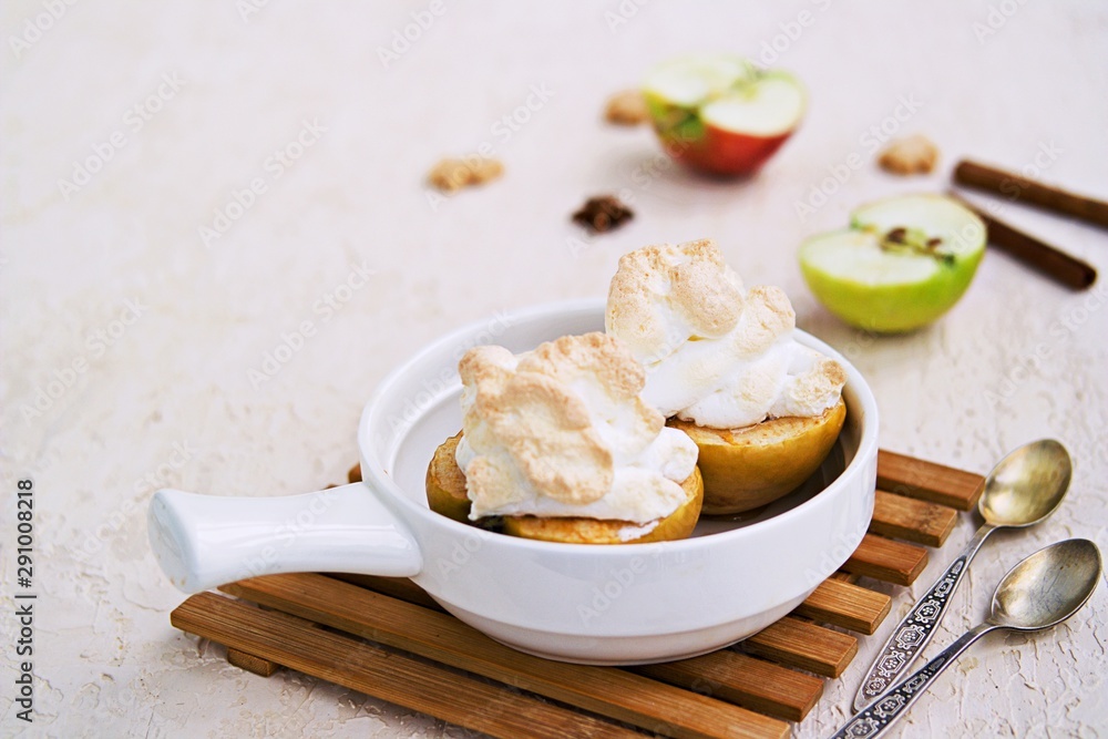 Autumn dessert, baked apples with meringue on a light concrete background. Thanksgiving Day. Harvest apples. Selective focus. Autumn dessert, baked apples with meringue on a light concrete background. Thanksgiving Day. Harvest apples. Selective focus.