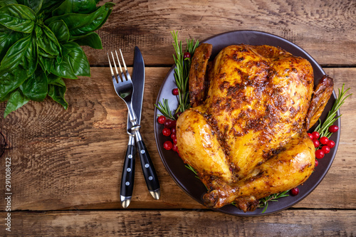 Baked chicken or turkey with herbs for festive dinner on wooden table. Christmas, Thanksgiving Day, holidays concept. Top view, copy space