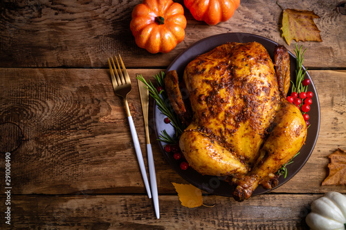Baked chicken for Thanksgiving Day. Roasted whole chicken or turkey with herbs for thanksgiving dinner on wooden table. Thanksgiving Day, holiday, Christmas concept