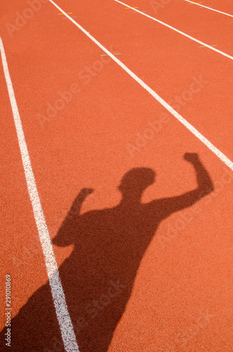 The shadow of man who show extend the arms on red running race track in sport stadium,abstract background, winner sport concept.